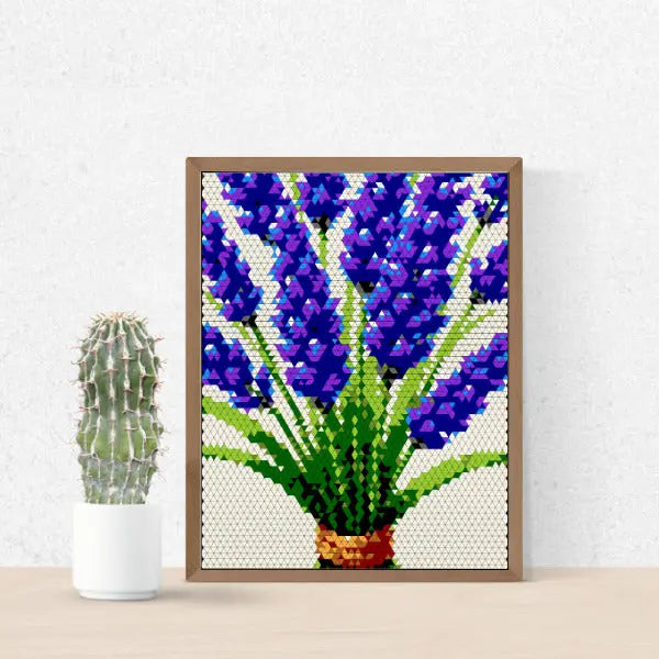 A framed piece of art depicting lavender flowers created with a triangular mosaic pattern, placed on a wooden surface.